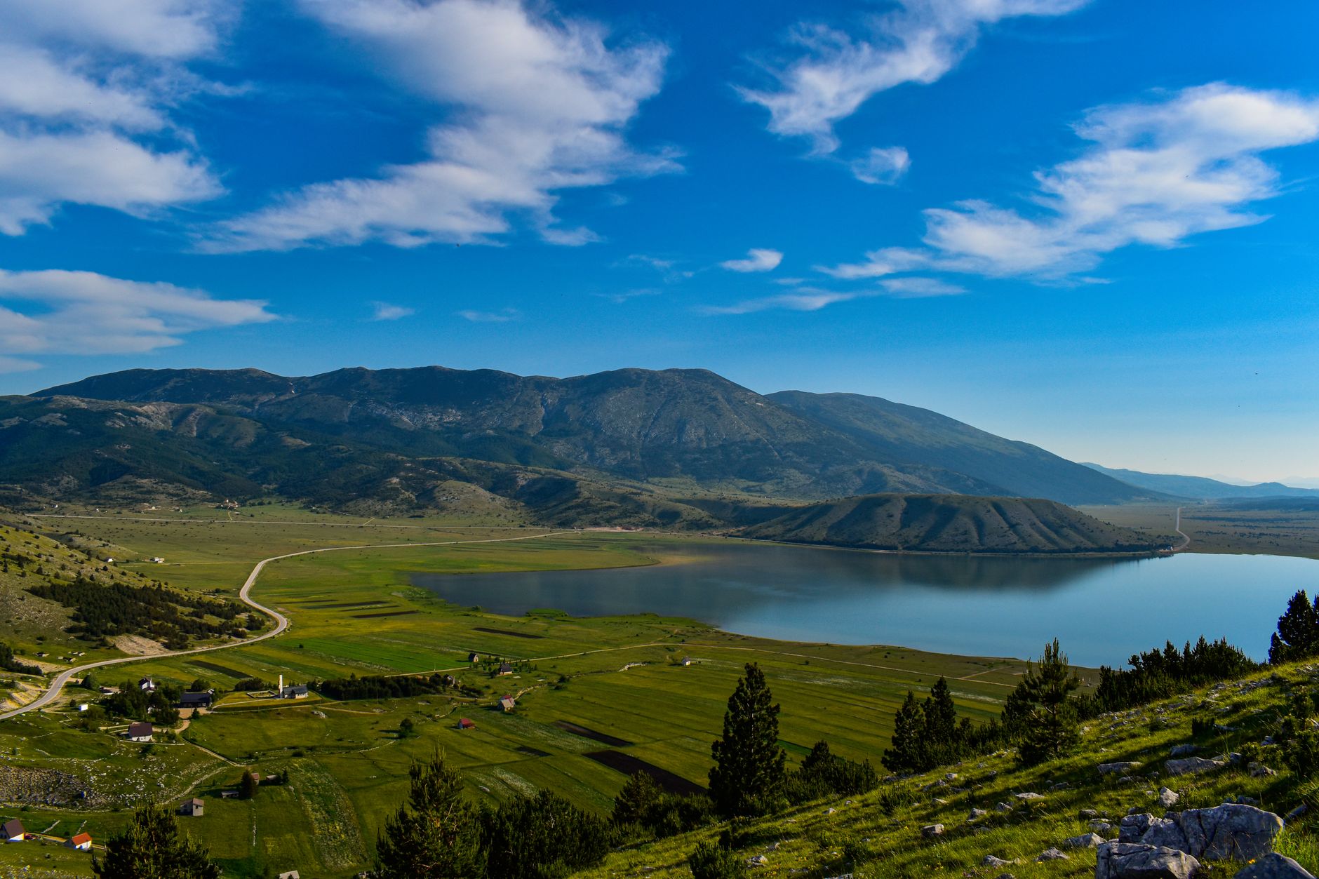 Breathtaking view of a serene lake and rolling hills under a clear blue sky in Bosnia and Herzegovina.