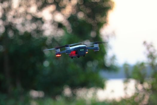 A drone flies amid blurred greenery, showcasing modern outdoor technology.
