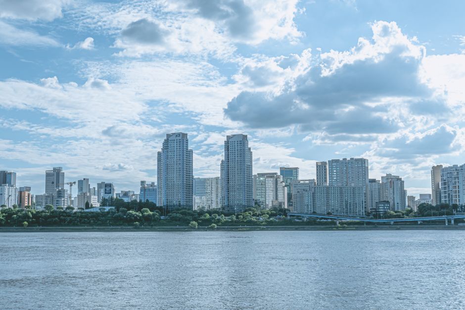 A vibrant city skyline featuring skyscrapers and a river under a cloudy sky. Ideal for urban-themed projects.