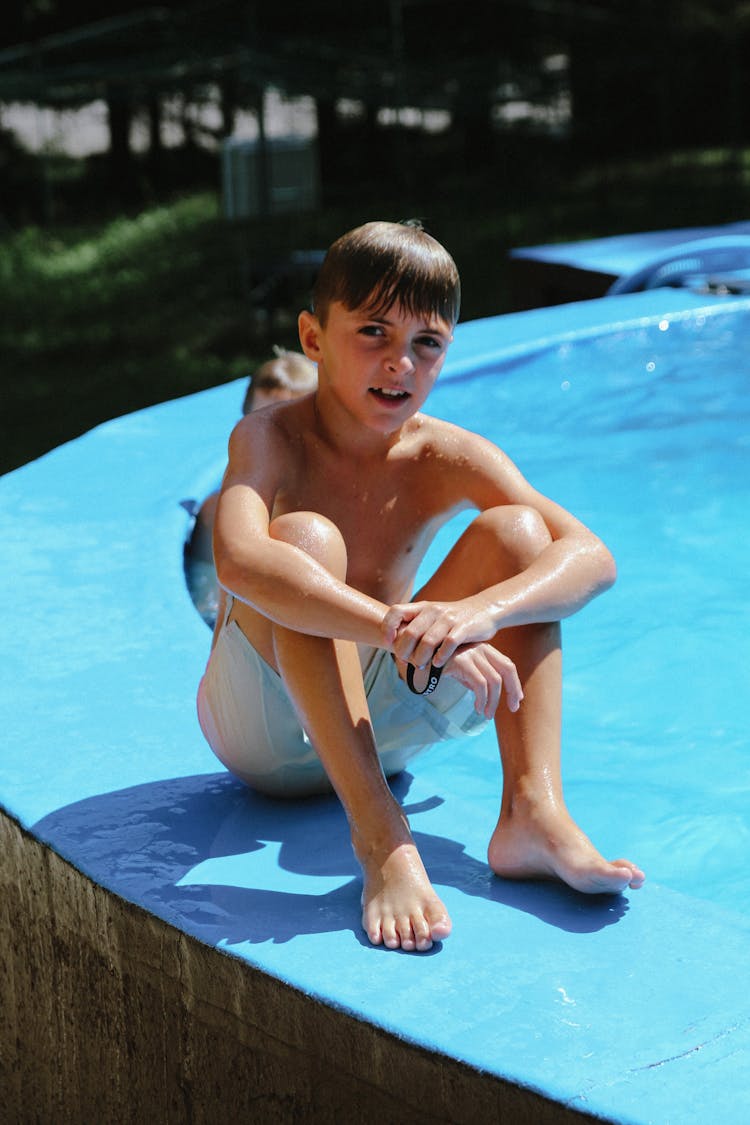 A Boy Sitting By A Poolside