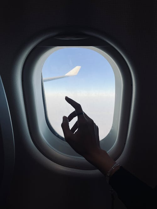 Free A Hand beside an Airplane Window Stock Photo