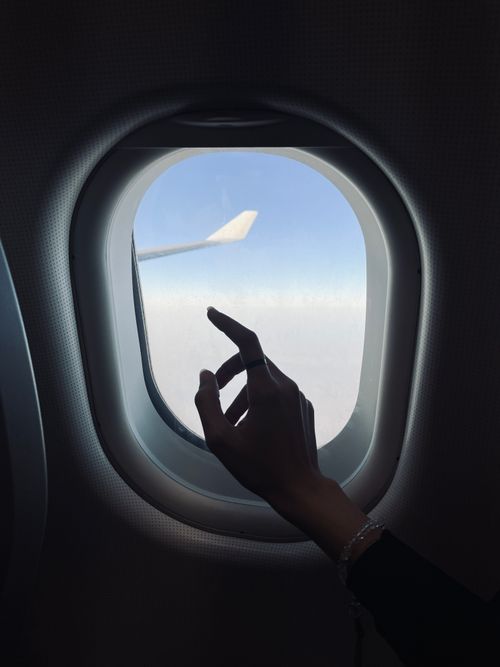 Free Silhouette of a hand reaching through airplane window towards the sky. Stock Photo