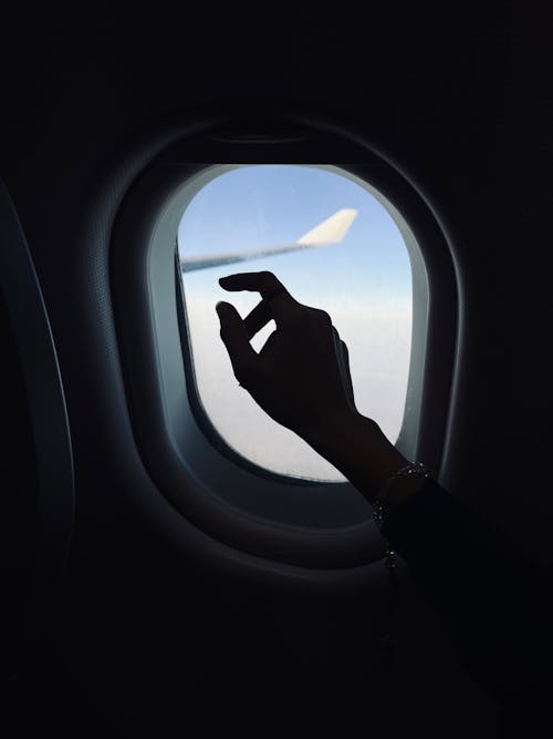 Free A Hand beside an Airplane Window Stock Photo