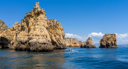 Free Dramatic rock formations rise from the tranquil blue waters under a clear sky. Stock Photo
