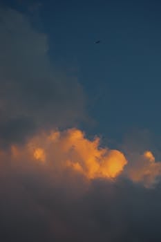Capture of dark clouds illuminated by the warm glow of sunset against a deep blue sky.