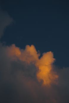 Vivid orange clouds illuminated by sunset against a deep blue sky, creating a dramatic scene.
