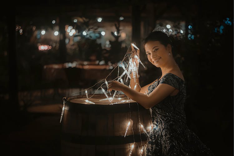 A Woman Wearing A Tiara And A Dress Holding Fairy Lights