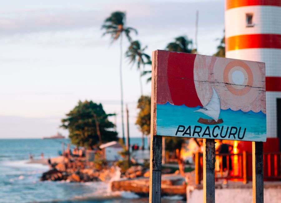 Scenic view of Paracuru beach with a distinctive lighthouse and colorful sign, Ceará, Brazil.