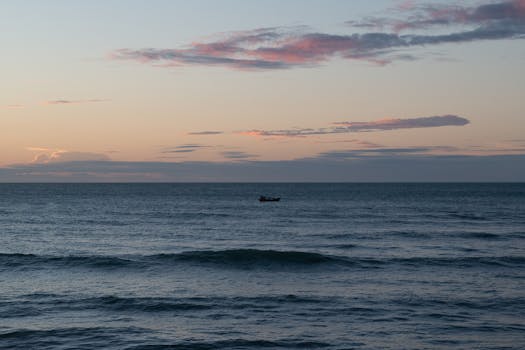 Captivating sunset over the ocean with a lone boat in Paracuru, Brazil.