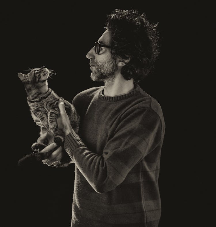 A Man In Gray Sweater Carrying A Cat