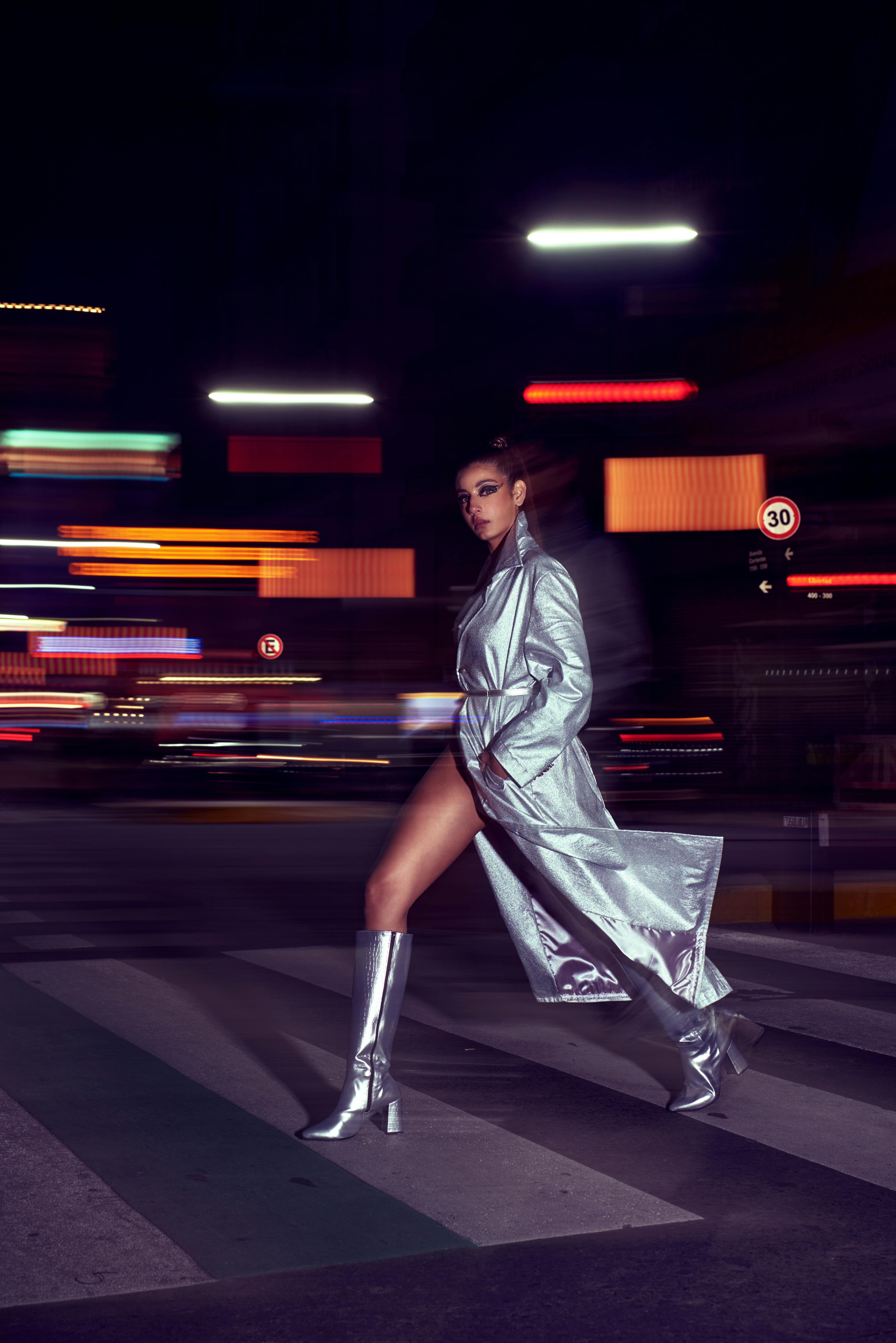 Stylish woman in silver outfit crossing street at night in Buenos Aires, Argentina.