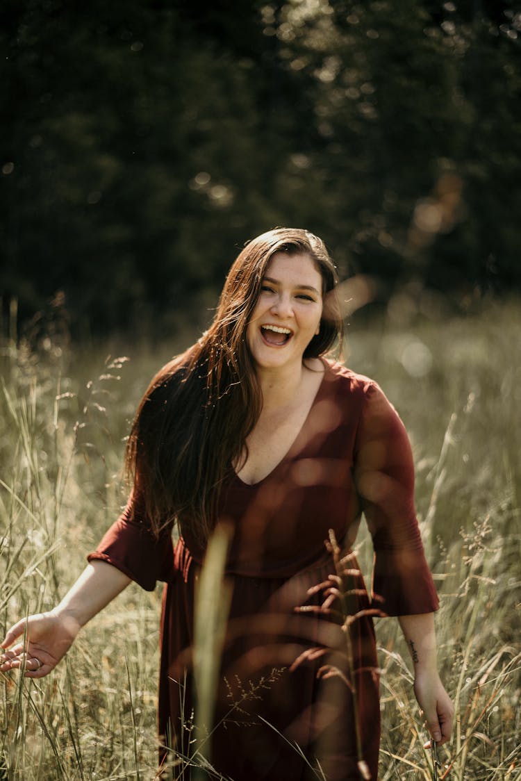 A Woman Laughing While Standing In The Field