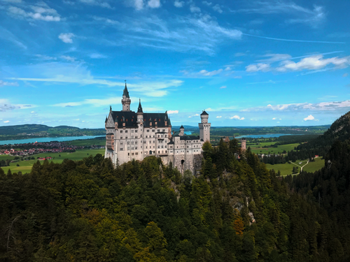 Free Stunning aerial view of Neuschwanstein Castle surrounded by lush forests and a vibrant landscape in Schwangau, Germany. Stock Photo