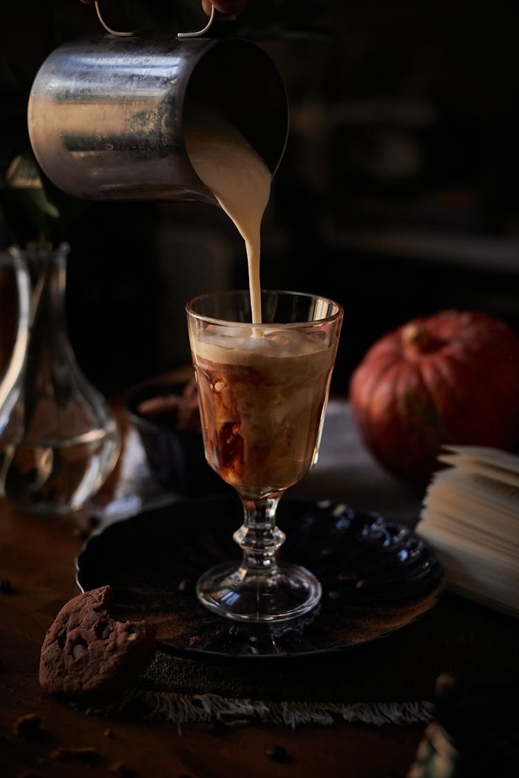 Close-Up Shot Of A Person Pouring Drink On A Glass