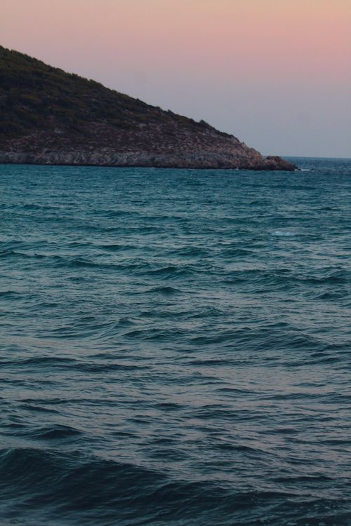 Free Tranquil image of ocean waves under pastel skies near a rocky cliff at twilight. Stock Photo