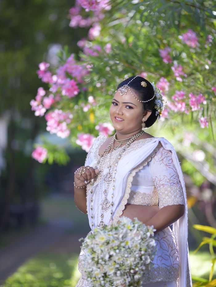 Kandyan bride in silver osariya with nalalpata beneath a blossom tree