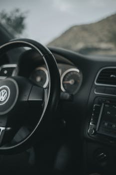 Detailed view of a car steering wheel and dashboard, showcasing control features.
