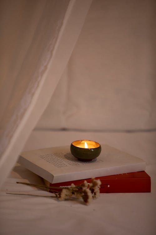 Burning Tea Candle on the Books and a Flower 