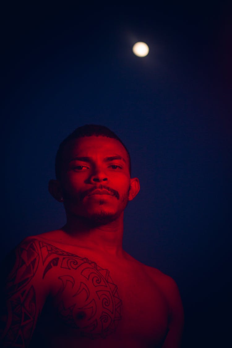 Shirtless Man With Tattoo Against Moon In Sky