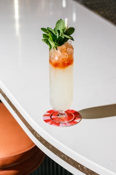 A vibrant mojito cocktail garnished with mint on a sleek white bar counter in Cuba, NY.