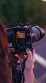 Close-up of a DSLR camera capturing a scenic sunset, highlighting creativity and technology.