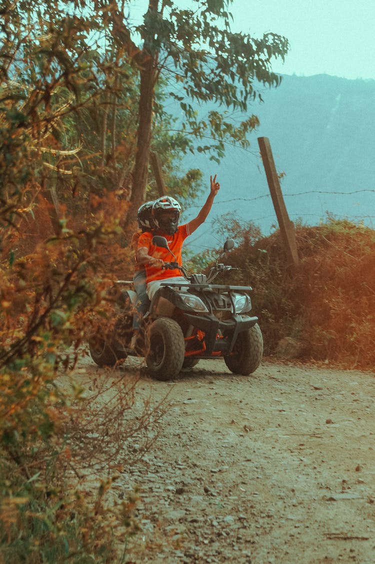 People Riding Quad Bike On Hill