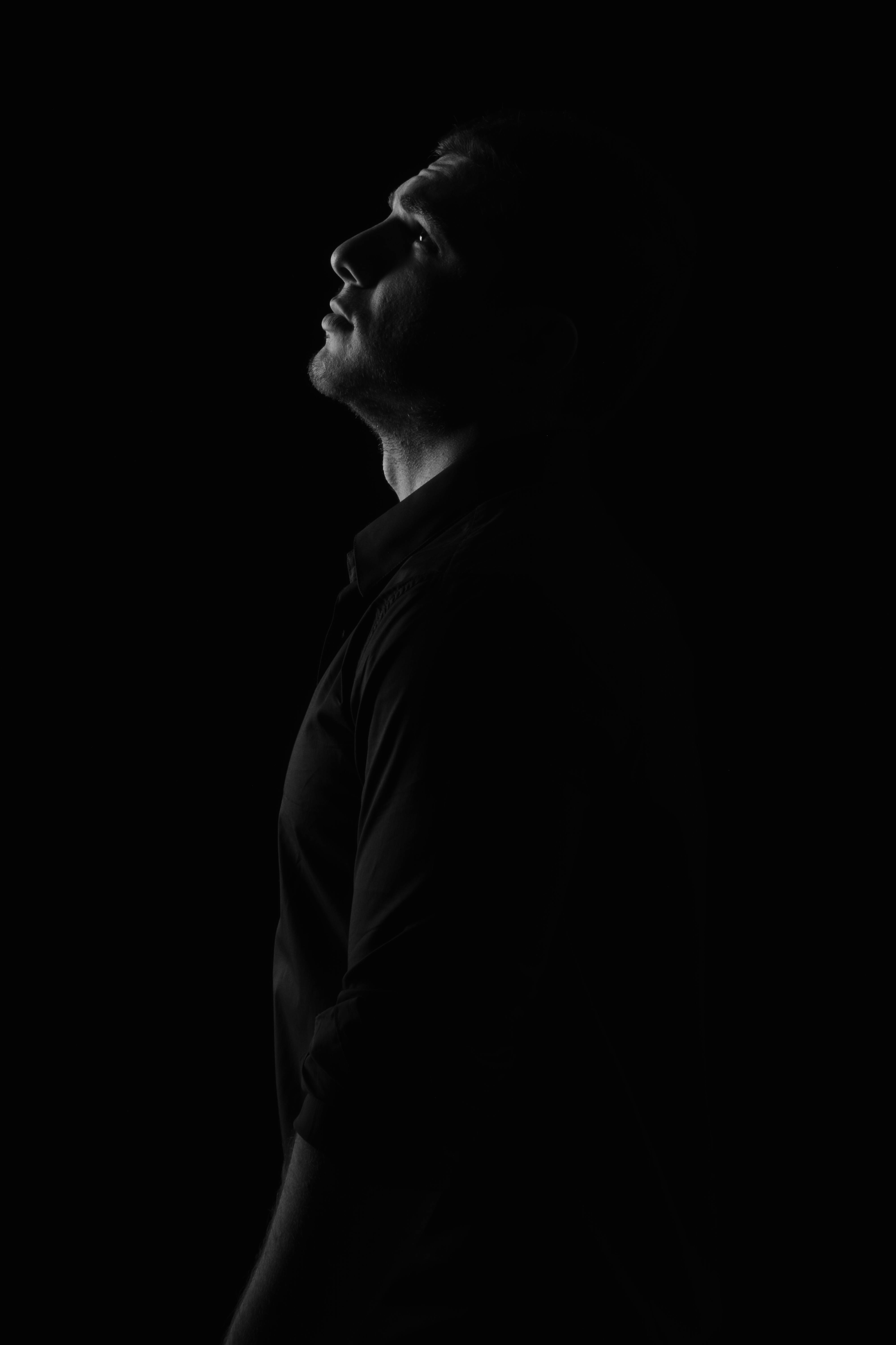 Elegant monochrome side view portrait of a man gazing upwards in a studio setting.