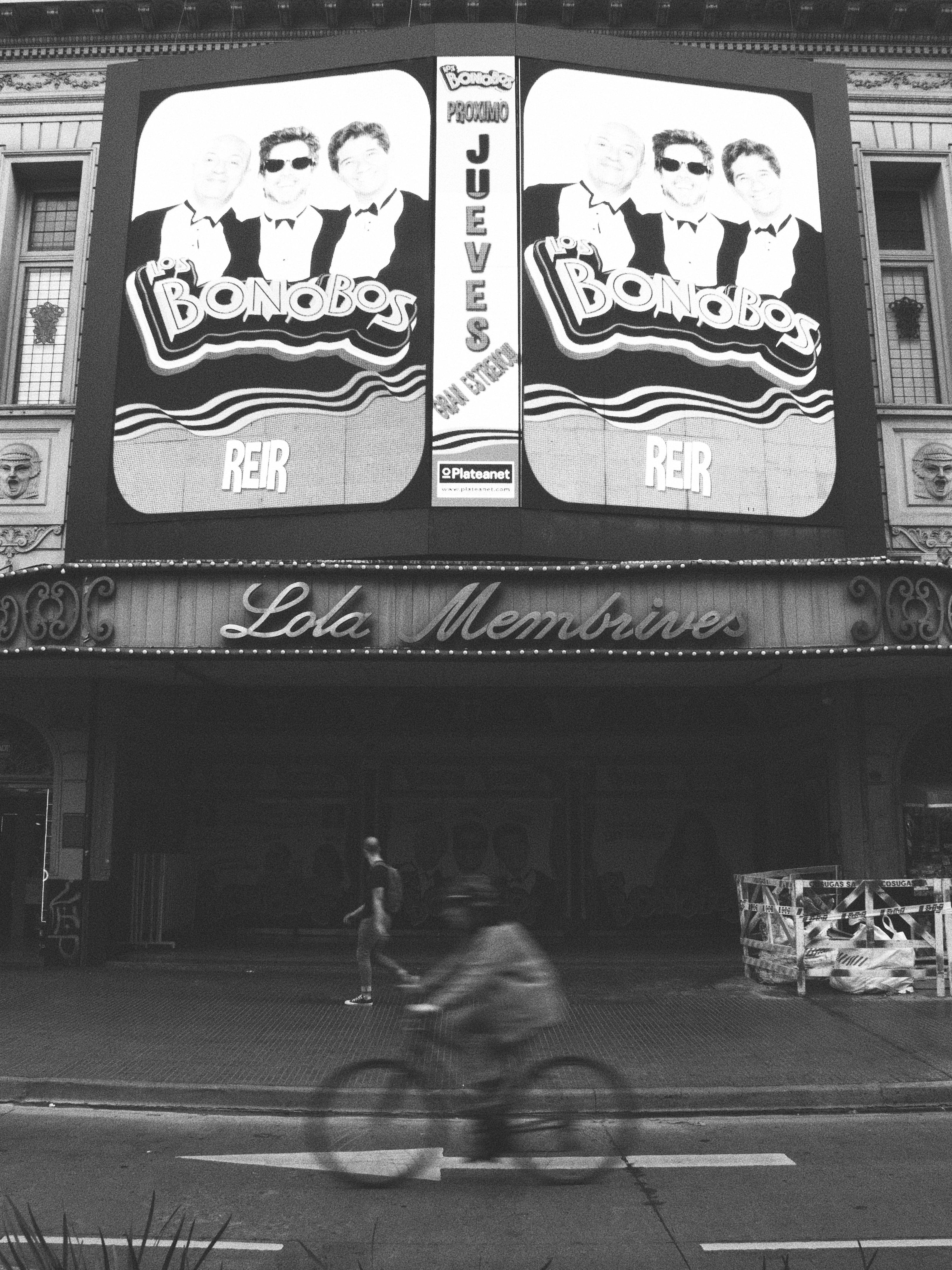 Free Black and white photo of a cyclist passing by a theater in Buenos Aires, Argentina. Stock Photo