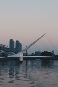Puente de la Mujer bridge and city skyline at sunset in Buenos Aires, Argentina.