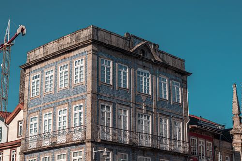 Free Charming urban residential building with classic blue tiles and intricate balconies set against a clear sky. Stock Photo