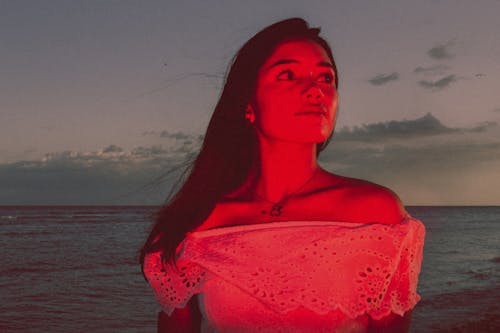 Woman Standing by Sea Shore under Red Light