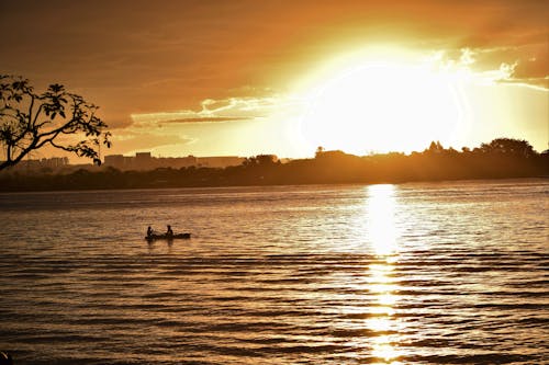 Silhouette of 2 People Riding Boat on Lake during Sunset