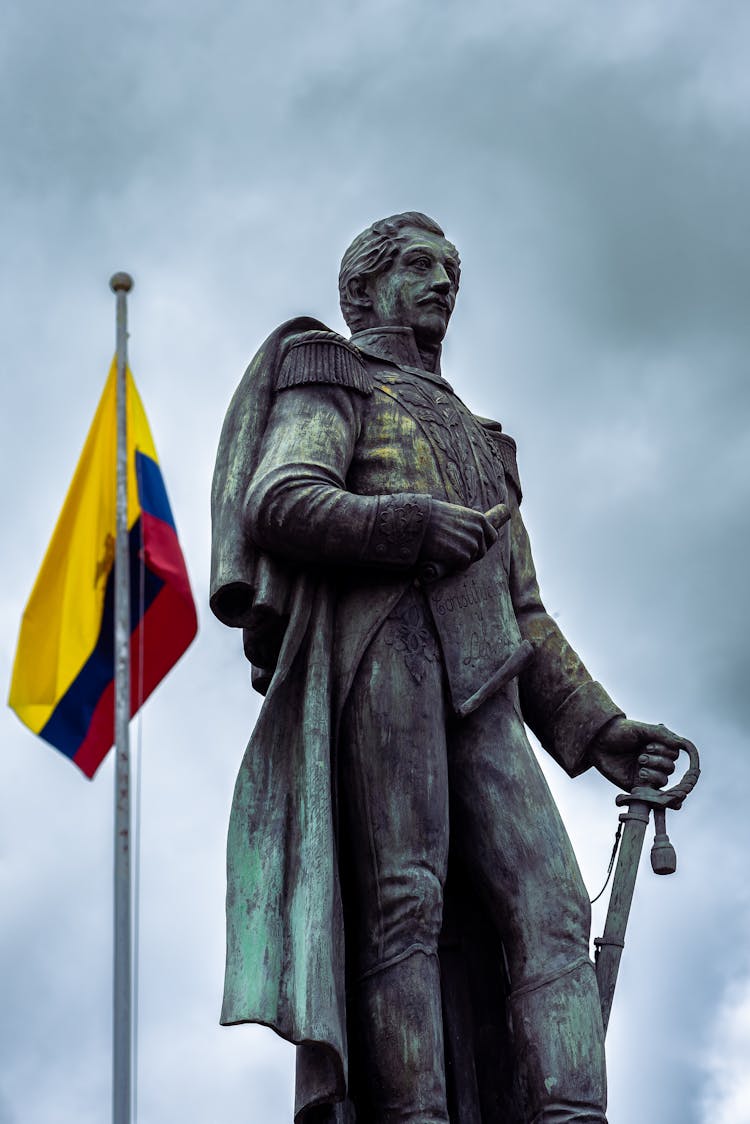 Bronze Monument And Flag On Sky Background