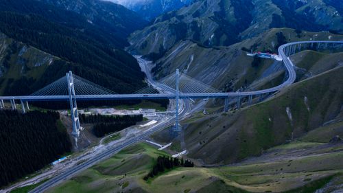 Free A scenic aerial view showcasing a suspension bridge amidst mountainous terrain, highlighting engineering marvel. Stock Photo