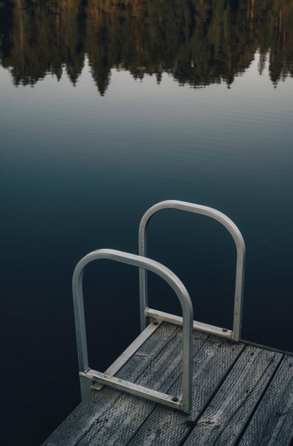 A serene lakeside view featuring a wooden pier and forest reflection, perfect for nature themes.