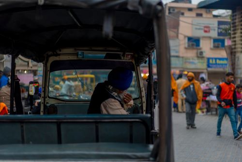 Free An urban street scene featuring a man seated in a motor vehicle, surrounded by bustling city life. Stock Photo