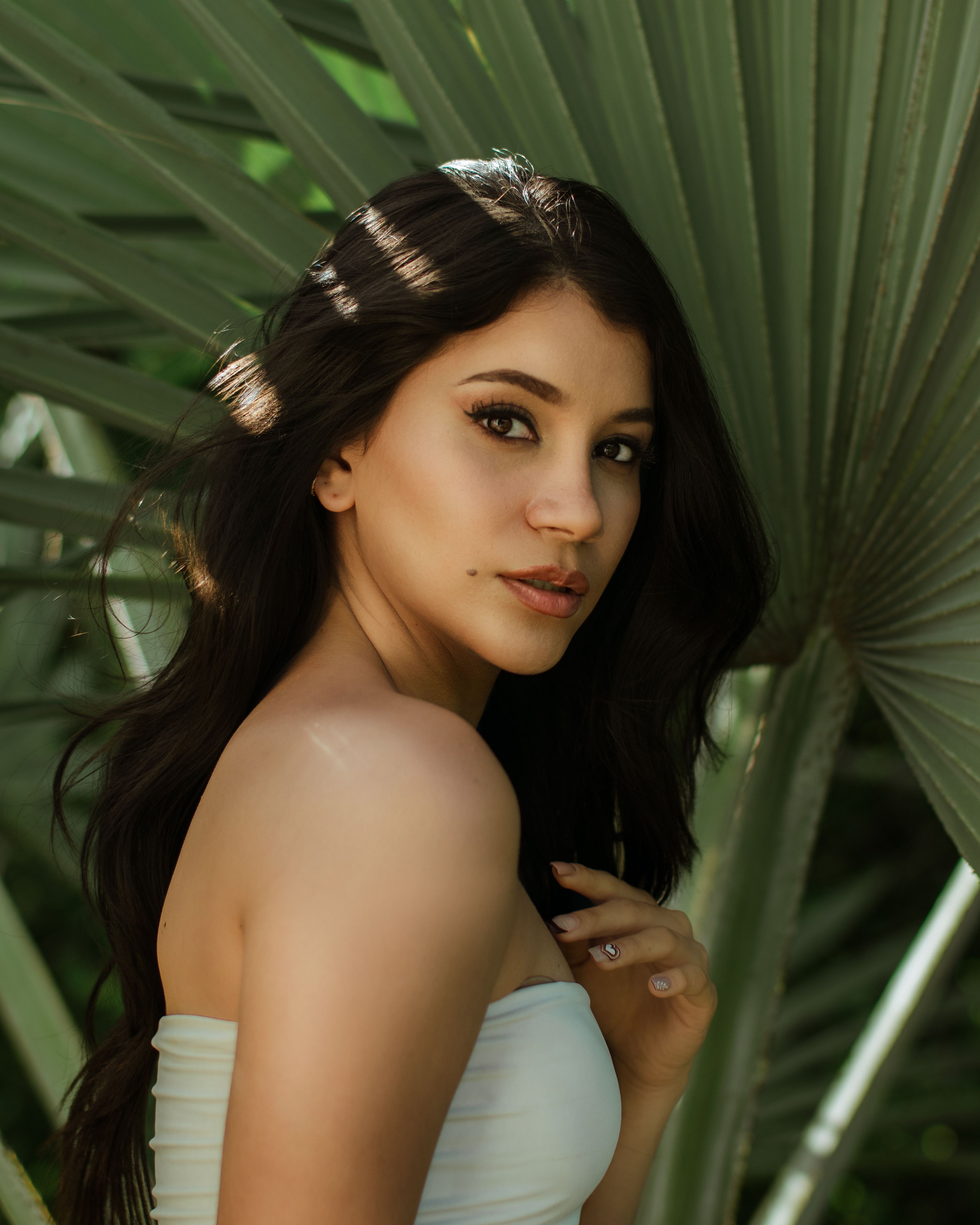 Young woman posing amidst tropical foliage. Natural lighting.