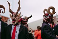 Men in elaborate devil masks perform a traditional folk dance outdoors.
