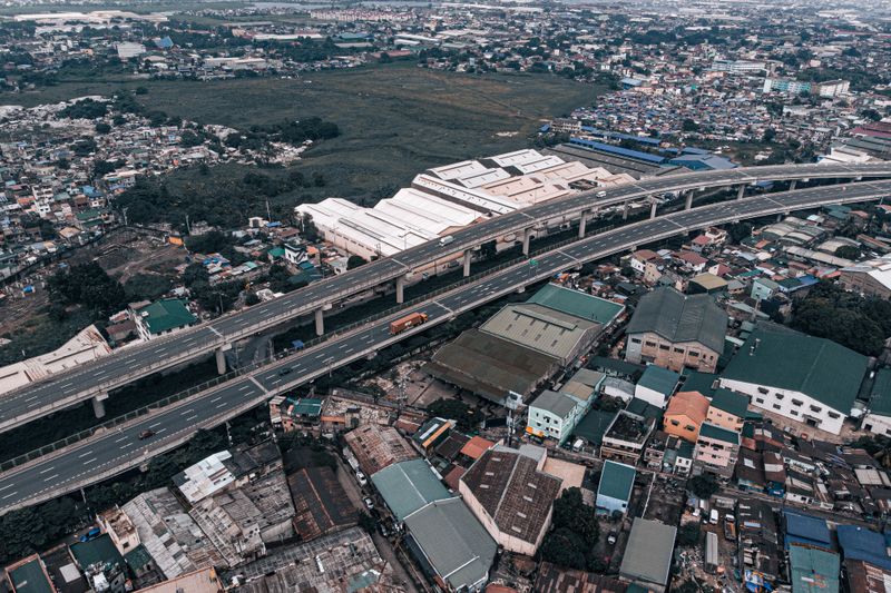 A vibrant aerial view of a bustling cityscape and elevated highway in the Philippines.