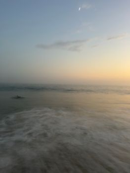 A serene ocean view at sunrise with a misty horizon and gentle waves.