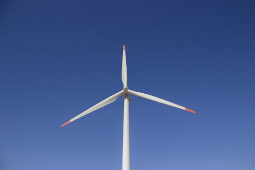 A wind turbine set against a clear blue sky, symbolizing clean and renewable energy.