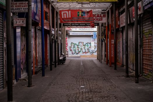 Empty alleyway in Istanbul featuring colorful graffiti and shuttered shops, highlighting urban street art.