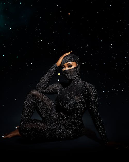 Sexy Woman in Black Costume with Glitters on Starry Background