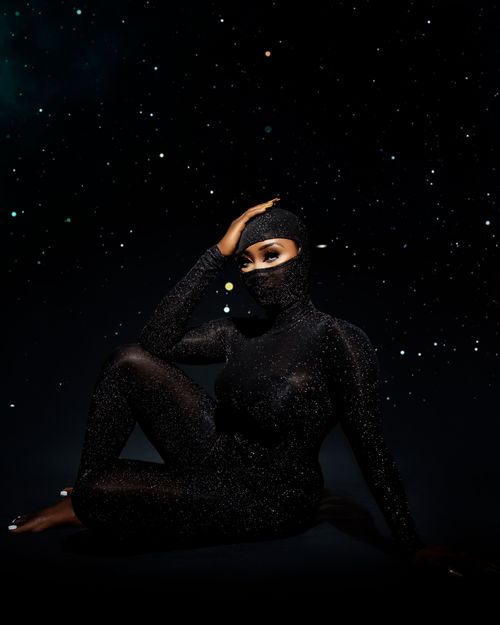 Free Elegant woman in a glittering costume poses against a starry background, embodying mystery and allure. Stock Photo
