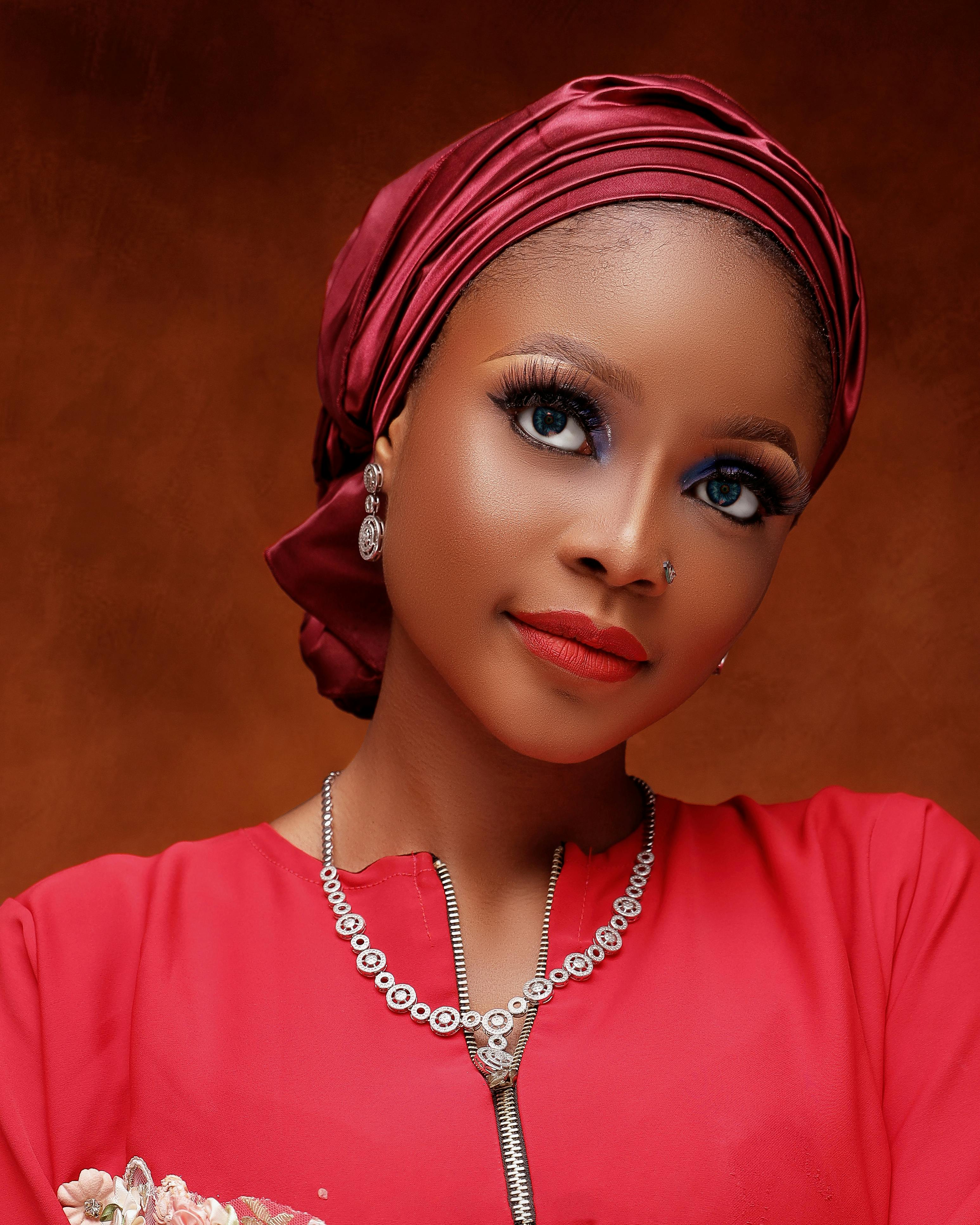 Elegant portrait of a woman with a red headdress and matching top, exuding confidence and beauty.