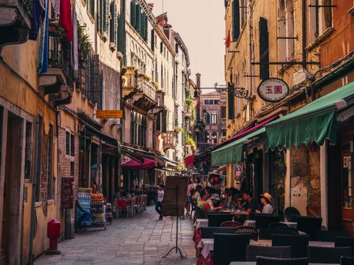 Free A lively street in Venice with cafes and historic architecture, capturing urban life. Stock Photo