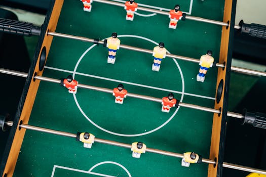 Top view of a foosball table with vibrant teams in play. Perfect for illustrating fun and competition.