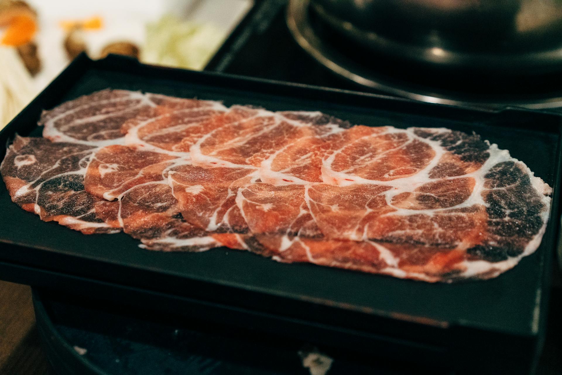 Thin Slice of Raw Meat on Black Ceramic Plate