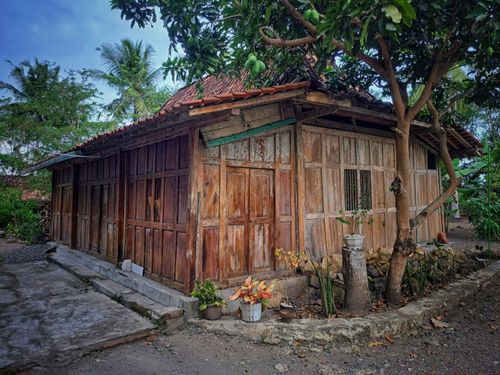 Free Charming wooden bungalow surrounded by greenery and trees in a serene rural setting. Stock Photo
