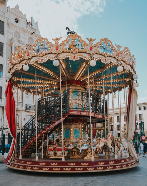 Free Beautiful vintage carousel with horses against a bright blue sky in an urban square Stock Photo